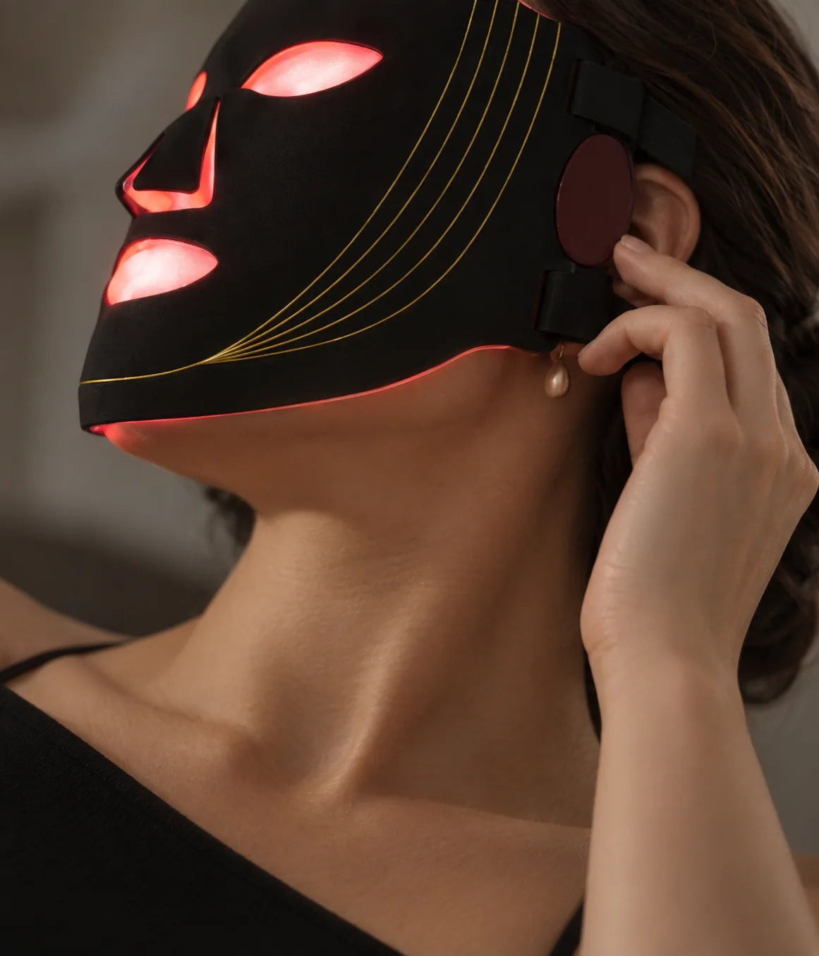 Close-up of a woman adjusting the Nuvorite black and gold light mask